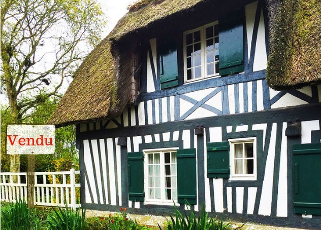 Half-timbered house with white walls and green wood panels with a "Sold" Sign