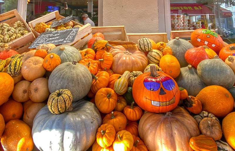 Market stall in France with pumpkins on one of them painted for halloween 