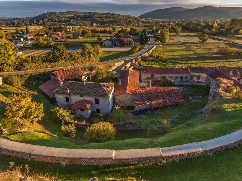 Aerial view of houses surrounded by grassy hills and mountains in Haute Garonne France